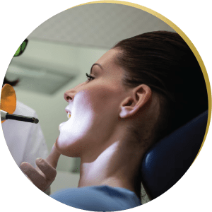 A woman undergoing a dental procedure for wisdom teeth removal with a curing light in a modern clinic. Professional dental care for a healthy smile