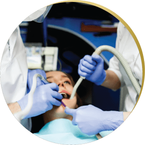 A female patient receiving professional wisdom teeth removal from two dentists wearing gloves and using dental instruments