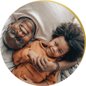 A happy father and child lying together, their bright smiles showcasing the benefits of cosmetic bonding in Las Vegas