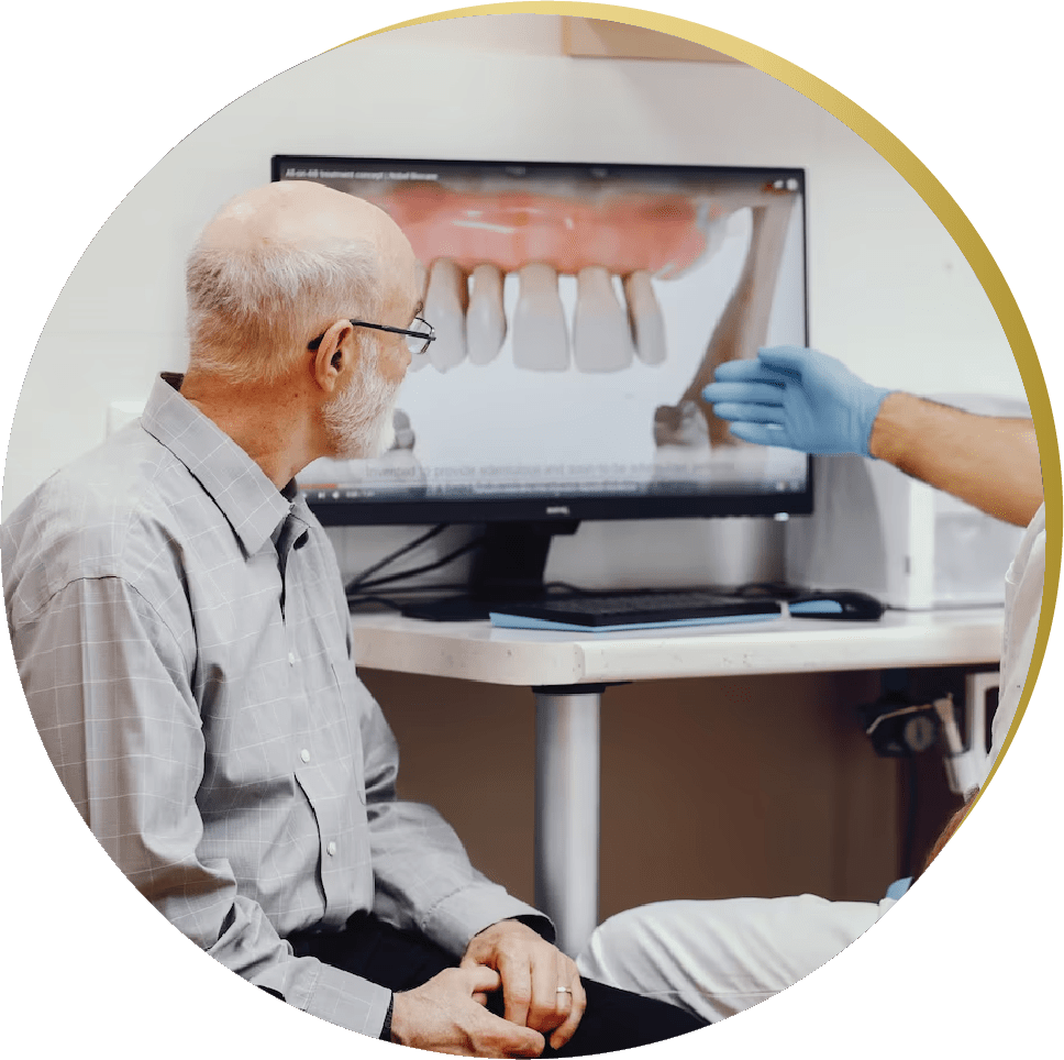 Elderly man consulting with a dentist about All on 4 Dental Implants, discussing treatment options displayed on a monitor.