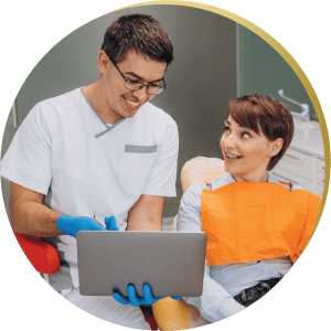 A dentist discussing a patient's dental health and preventive care plan using a laptop
