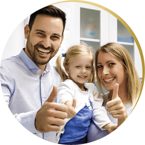 A family of three with wide smiles and thumbs up in a dental office, highlighting the family-friendly cosmetic dentistry services in Las Vegas