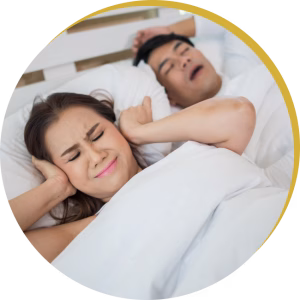 Wife covering her ears while husband snores loudly before starting sleep apnea treatment.